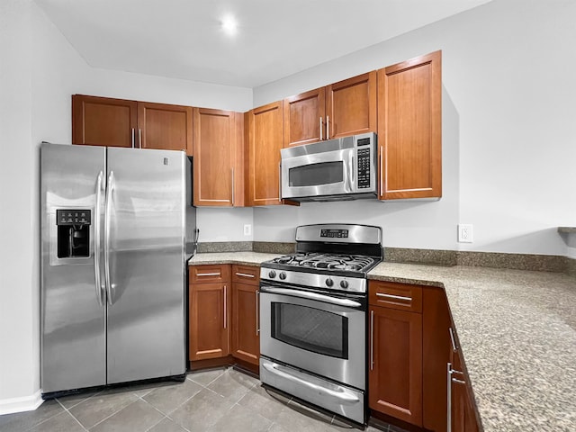 kitchen with stainless steel appliances, light stone countertops, and light tile patterned floors