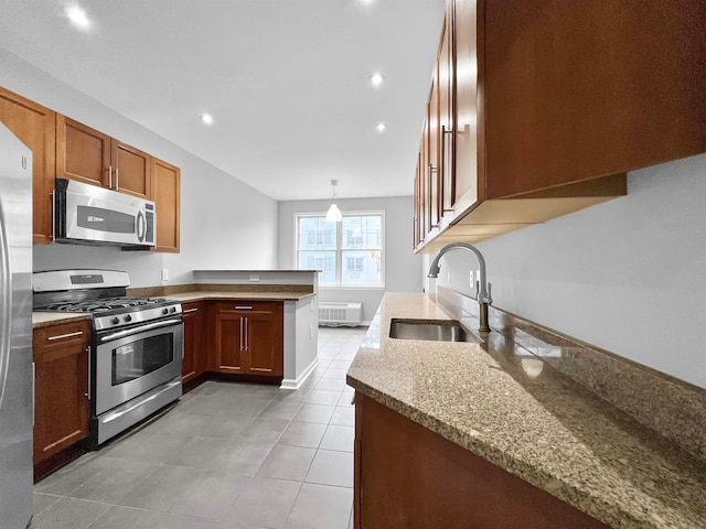 kitchen with stainless steel appliances, sink, kitchen peninsula, light stone countertops, and decorative light fixtures