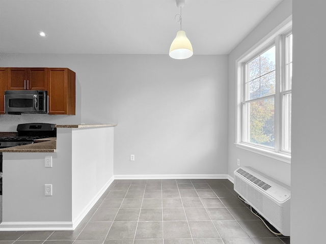 kitchen featuring a wall mounted AC, dark stone countertops, light tile patterned floors, hanging light fixtures, and electric range