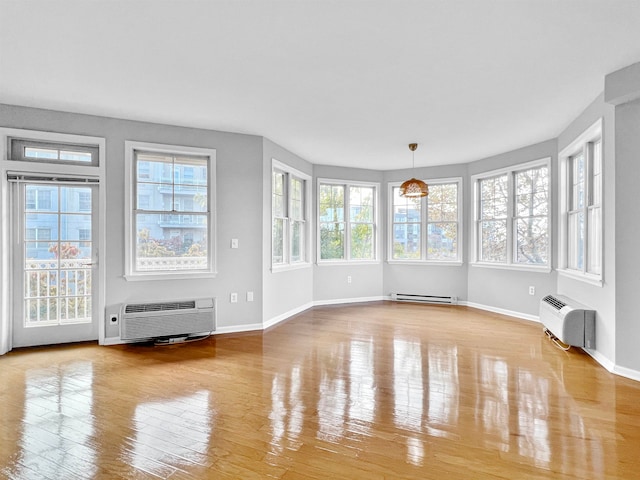 unfurnished sunroom with a wall unit AC and a baseboard heating unit