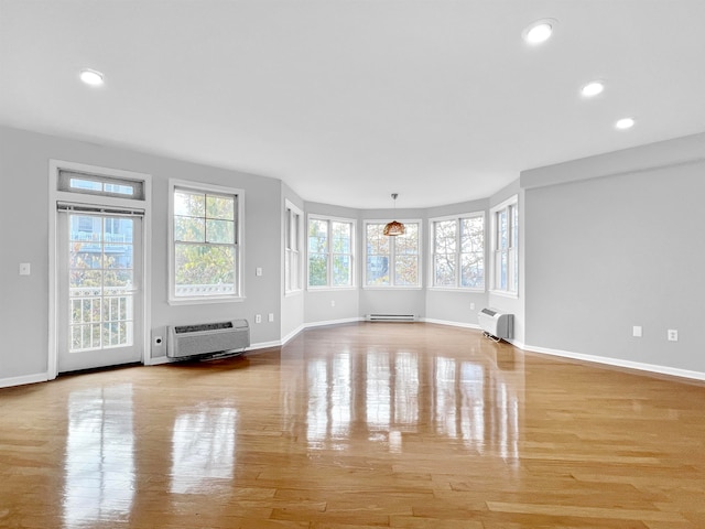 unfurnished living room featuring an AC wall unit, a baseboard radiator, and light hardwood / wood-style flooring