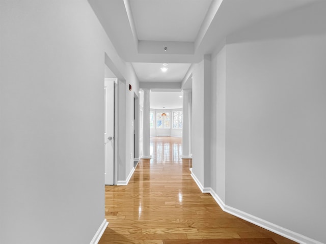 hallway with decorative columns and light hardwood / wood-style floors