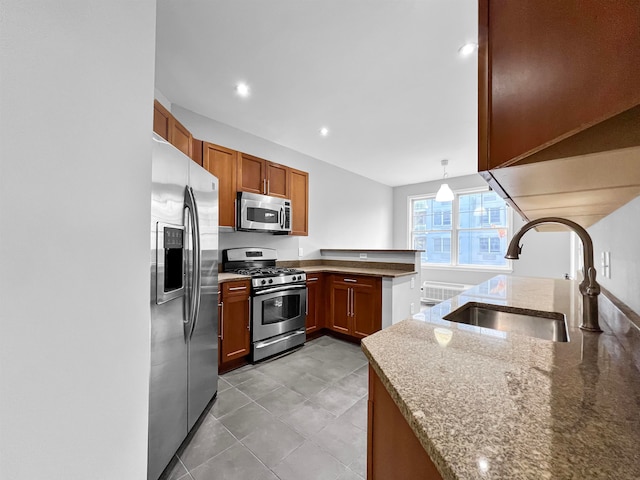 kitchen with stainless steel appliances, sink, kitchen peninsula, light stone counters, and hanging light fixtures