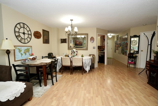 dining room with an inviting chandelier, light hardwood / wood-style flooring, and a textured ceiling