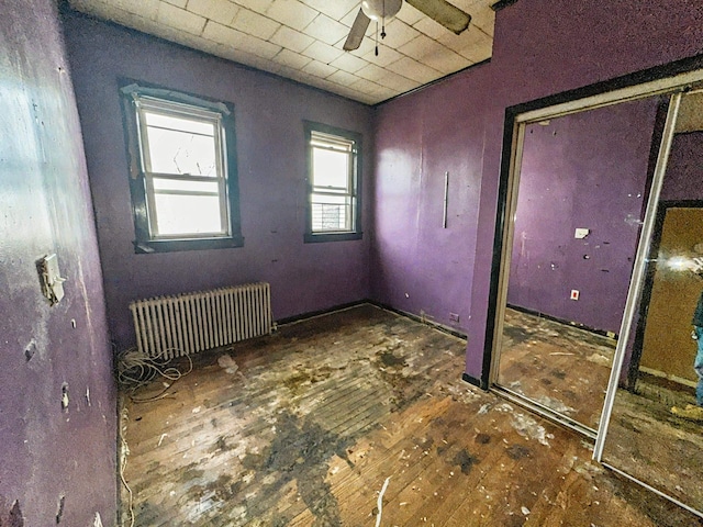 unfurnished bedroom featuring radiator heating unit and a closet