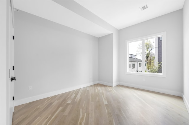 spare room featuring light wood-type flooring, visible vents, and baseboards