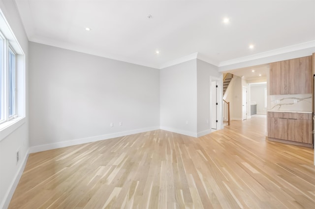 unfurnished living room with light wood-type flooring, crown molding, and baseboards