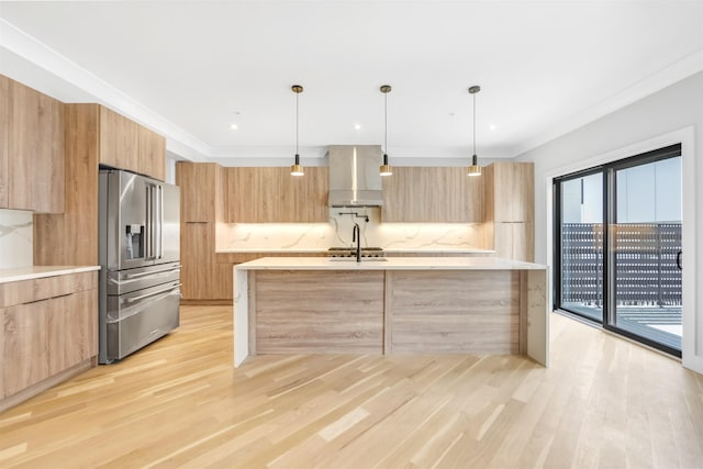 kitchen with wall chimney range hood, light brown cabinets, modern cabinets, and high end fridge