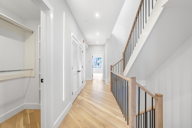 hallway with light wood finished floors, stairway, recessed lighting, and baseboards