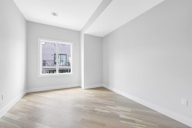 unfurnished room with light wood-style floors, visible vents, and baseboards