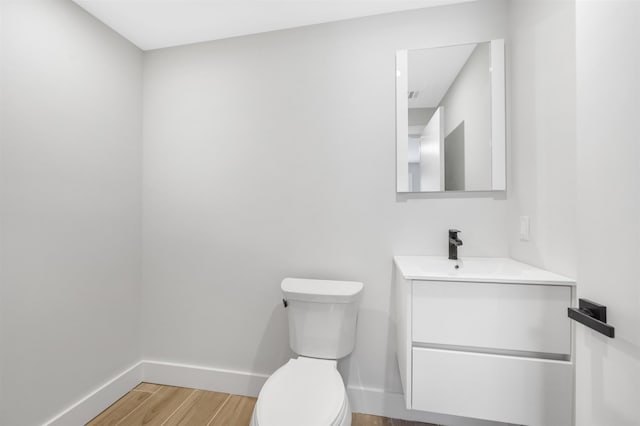 bathroom featuring toilet, wood finished floors, vanity, and baseboards