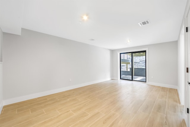 empty room with light wood-style flooring, visible vents, and baseboards