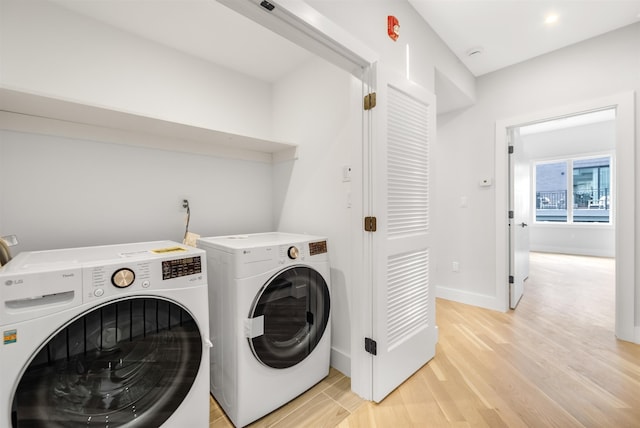 laundry room with light wood-type flooring, laundry area, baseboards, and separate washer and dryer