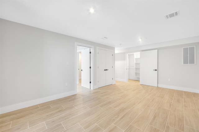 unfurnished room featuring light wood-type flooring, visible vents, and baseboards