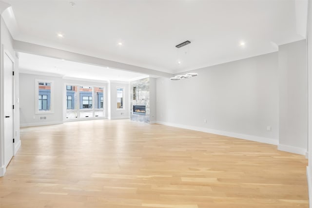 unfurnished living room featuring baseboards, crown molding, a stone fireplace, light wood-style floors, and recessed lighting