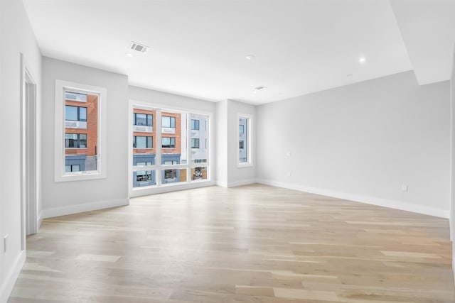 empty room featuring baseboards, visible vents, and light wood-style floors