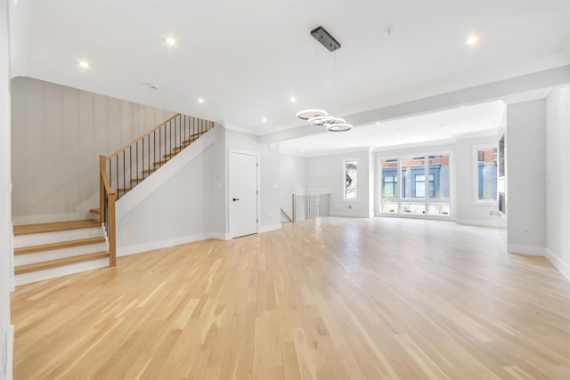 unfurnished living room featuring recessed lighting, stairway, light wood-style floors, a chandelier, and baseboards