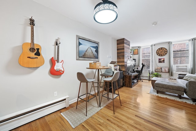 dining area featuring cooling unit, light hardwood / wood-style floors, and a baseboard heating unit