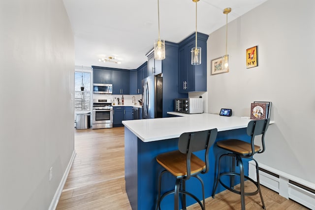 kitchen with stainless steel appliances, blue cabinets, hanging light fixtures, and kitchen peninsula