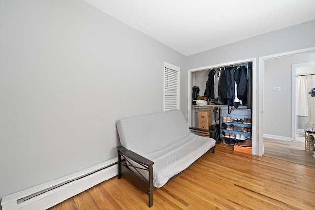 living area featuring wood-type flooring and a baseboard heating unit