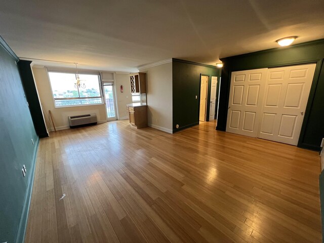 100 Manhattan Ave Unit 1104, Union City, NJ 07087 - unfurnished living room featuring ornamental molding, wood finished floors, a wall mounted air conditioner, and a chandelier