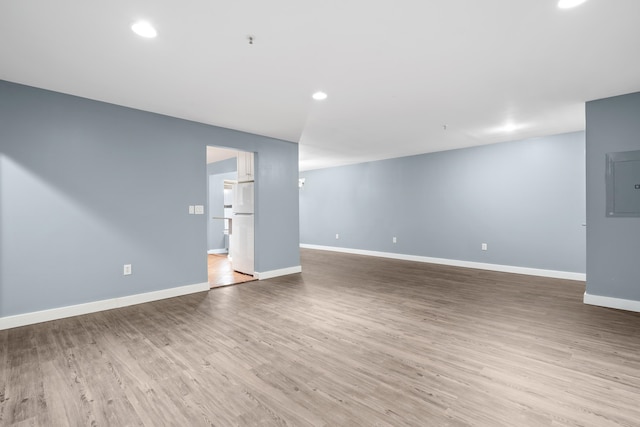 interior space featuring electric panel, light hardwood / wood-style floors, and white refrigerator