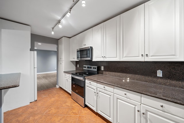 kitchen with appliances with stainless steel finishes, white cabinetry, and dark stone countertops