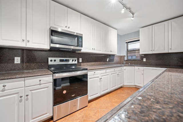 kitchen with rail lighting, stainless steel appliances, sink, light tile patterned floors, and white cabinetry