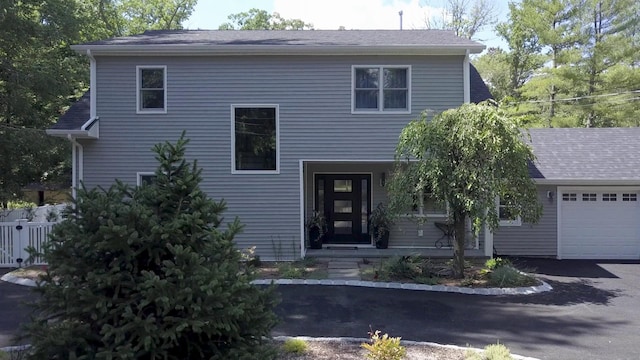 view of front of house featuring an attached garage, driveway, and roof with shingles