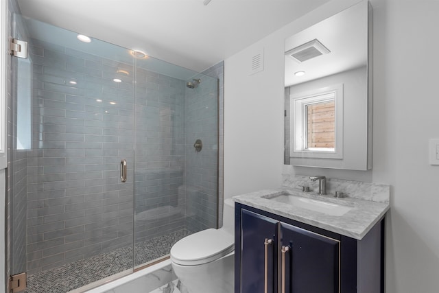 bathroom featuring vanity, toilet, and a shower with shower door