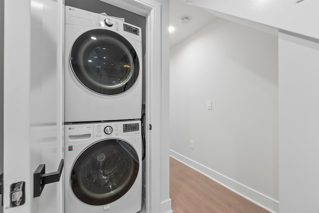 laundry room featuring stacked washer and dryer and light hardwood / wood-style floors