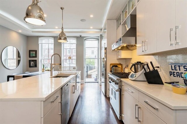 225 8th St, Jersey City, NJ 07302 - kitchen featuring wall chimney exhaust hood, appliances with stainless steel finishes, a kitchen island with sink, decorative backsplash, and dark wood-type flooring