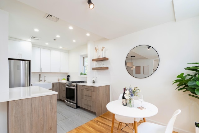 110 Morris St Unit 3R, Jersey City, NJ 07302 - kitchen featuring stainless steel appliances, modern cabinets, decorative backsplash, light countertops, and white cabinets