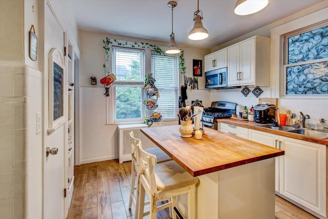 8212 2nd Ave, North Bergen, NJ 07047 - kitchen featuring appliances with stainless steel finishes, wooden counters, radiator, and light wood-style floors