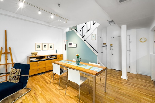 dining area featuring stairs, light wood-style floors, and track lighting