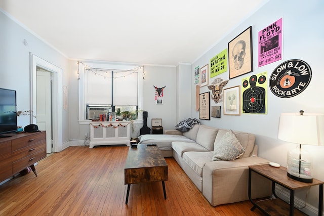 living room featuring cooling unit, crown molding, and light wood-type flooring