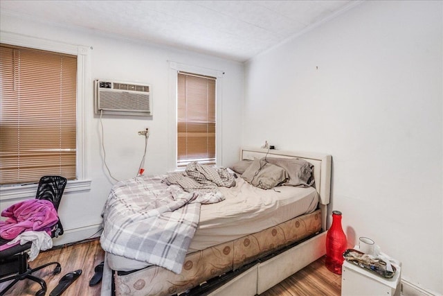 bedroom featuring hardwood / wood-style flooring, baseboard heating, and a wall mounted air conditioner