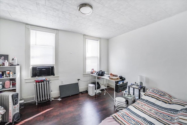 bedroom with dark wood-type flooring, cooling unit, and radiator heating unit