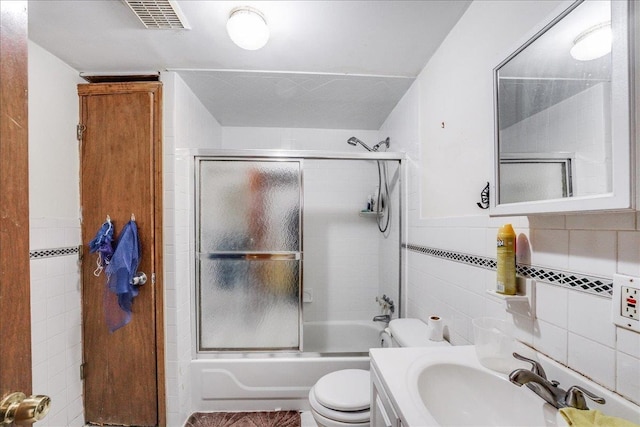 full bathroom with vanity, bath / shower combo with glass door, backsplash, tile walls, and toilet