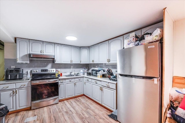 kitchen featuring light hardwood / wood-style floors, decorative backsplash, sink, appliances with stainless steel finishes, and gray cabinetry