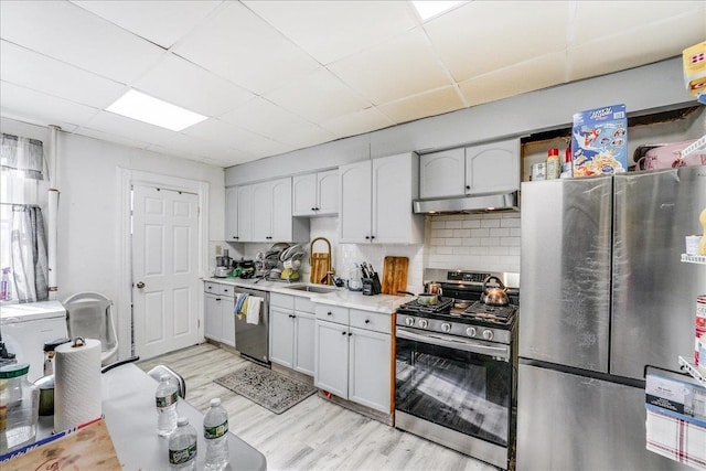 kitchen featuring a drop ceiling, decorative backsplash, sink, appliances with stainless steel finishes, and white cabinets