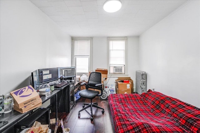 bedroom with hardwood / wood-style flooring, cooling unit, and radiator heating unit