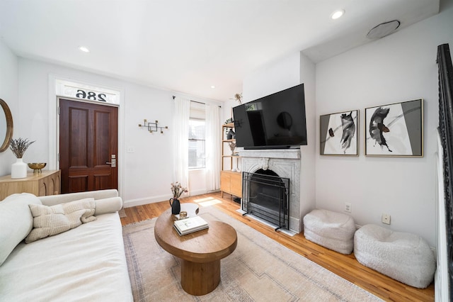 living room featuring recessed lighting, baseboards, light wood finished floors, and a fireplace