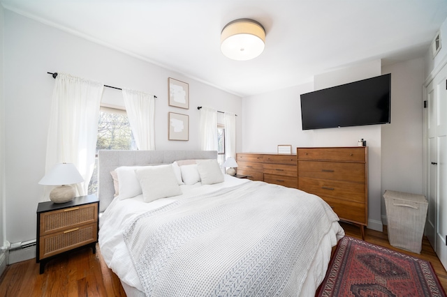 bedroom with wood finished floors and baseboard heating
