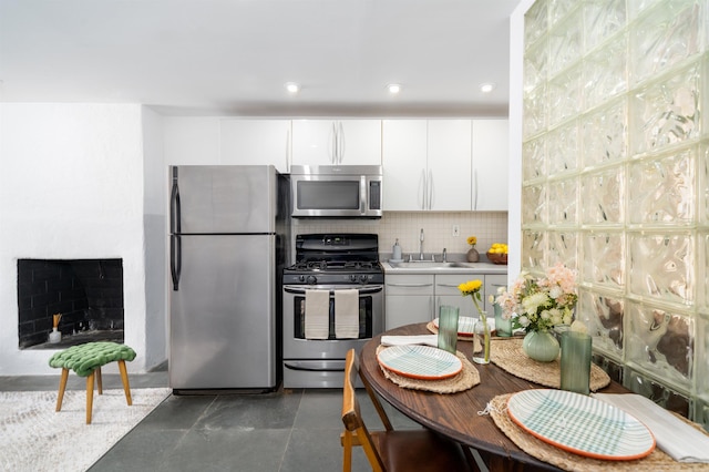 kitchen featuring appliances with stainless steel finishes, a sink, white cabinetry, tasteful backsplash, and modern cabinets