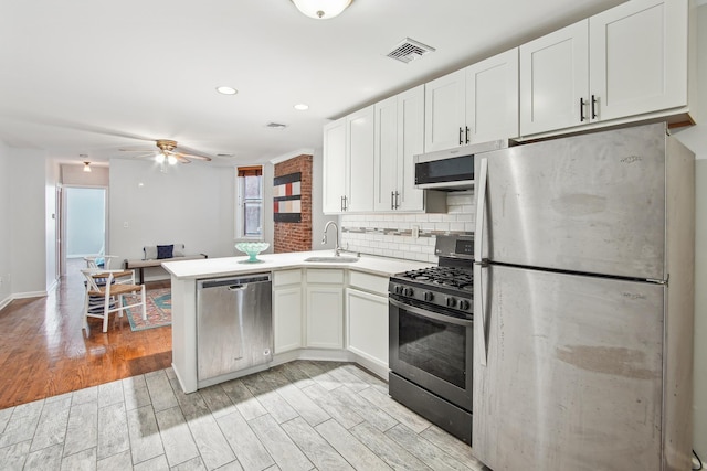 kitchen with kitchen peninsula, stainless steel appliances, sink, light hardwood / wood-style flooring, and white cabinets