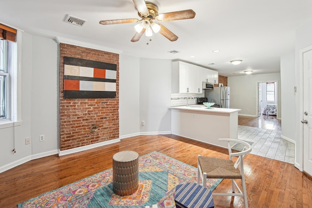 living room with light hardwood / wood-style flooring, ceiling fan, and sink