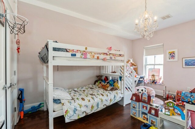 bedroom with a notable chandelier, wood finished floors, and visible vents