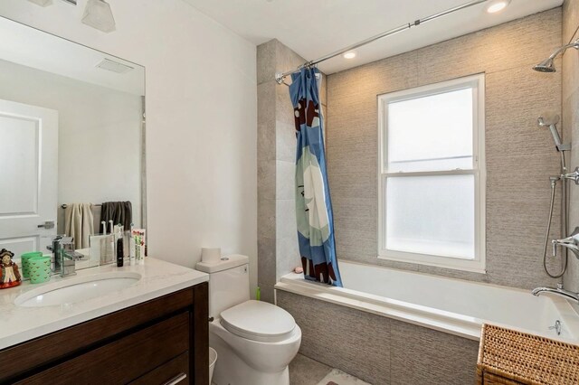 bathroom featuring vanity, tiled shower / bath, and toilet