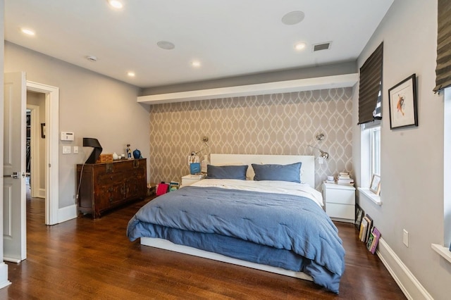 bedroom with baseboards, wallpapered walls, wood finished floors, and an accent wall